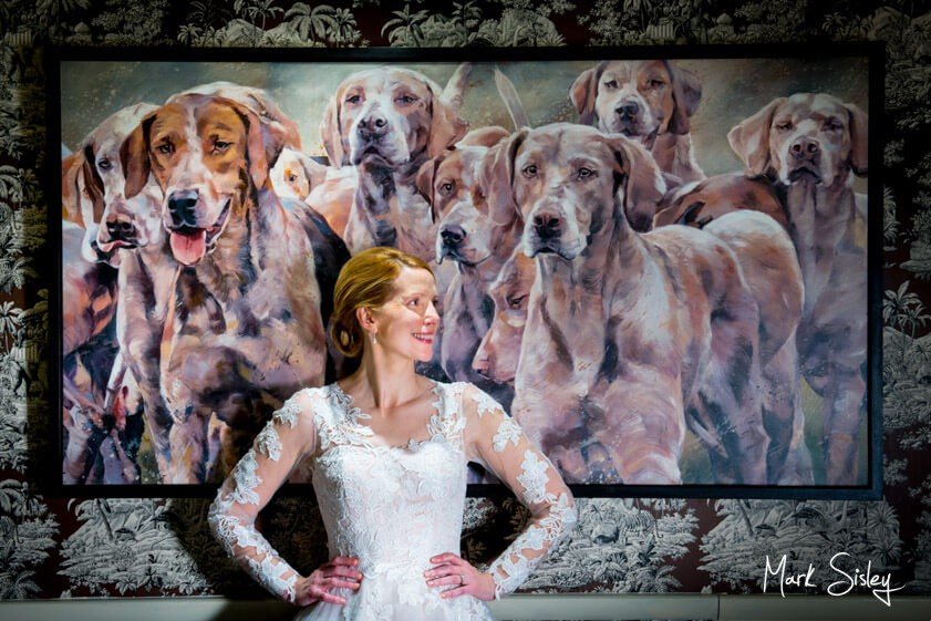 Bride posed in front of painting of dogs - Mark Sisley Photography