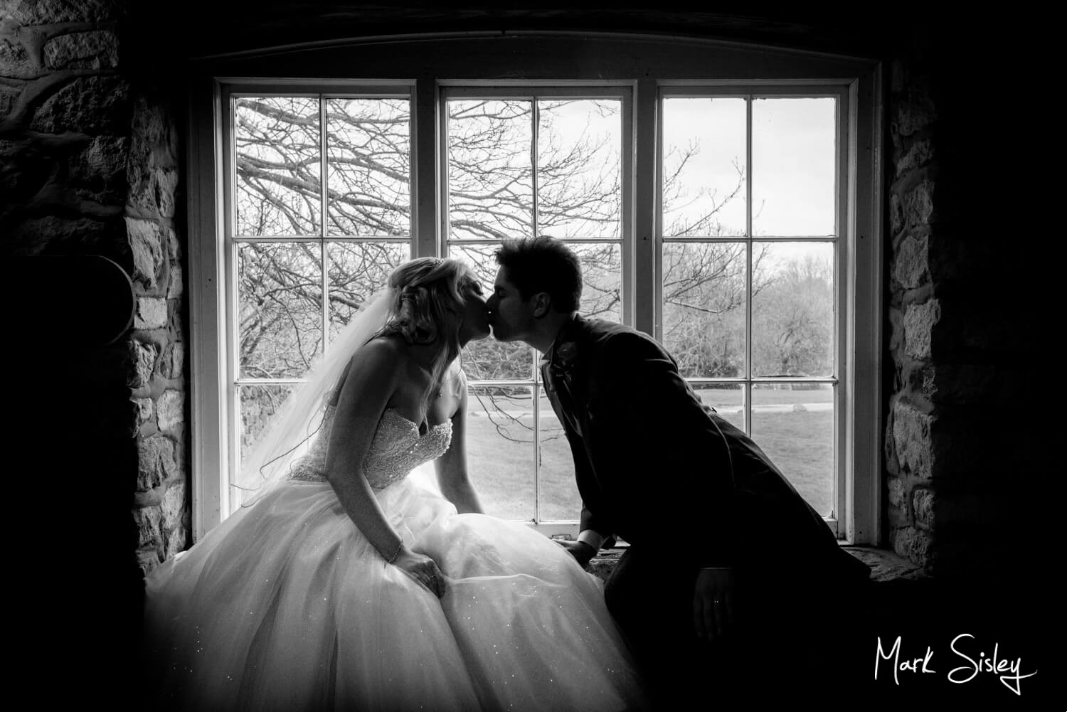 Notley Tythe Barn wedding photography - silhouette image of bride and groom kissing in the window