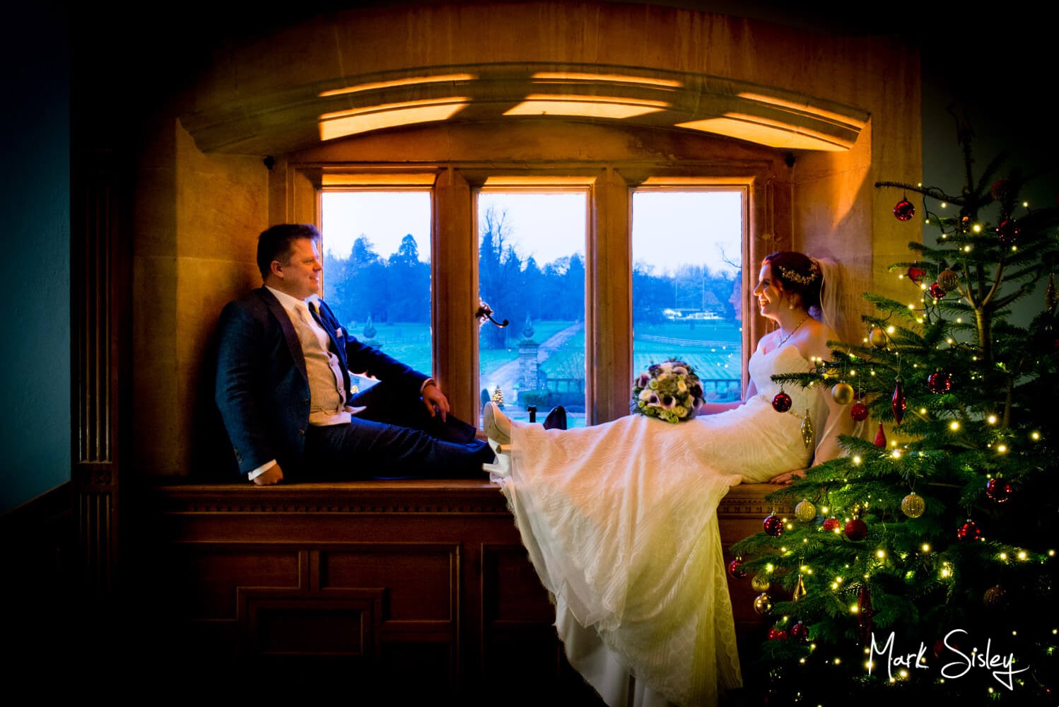 Eynsham Hall winter wedding pose in the window by the Christmas tree