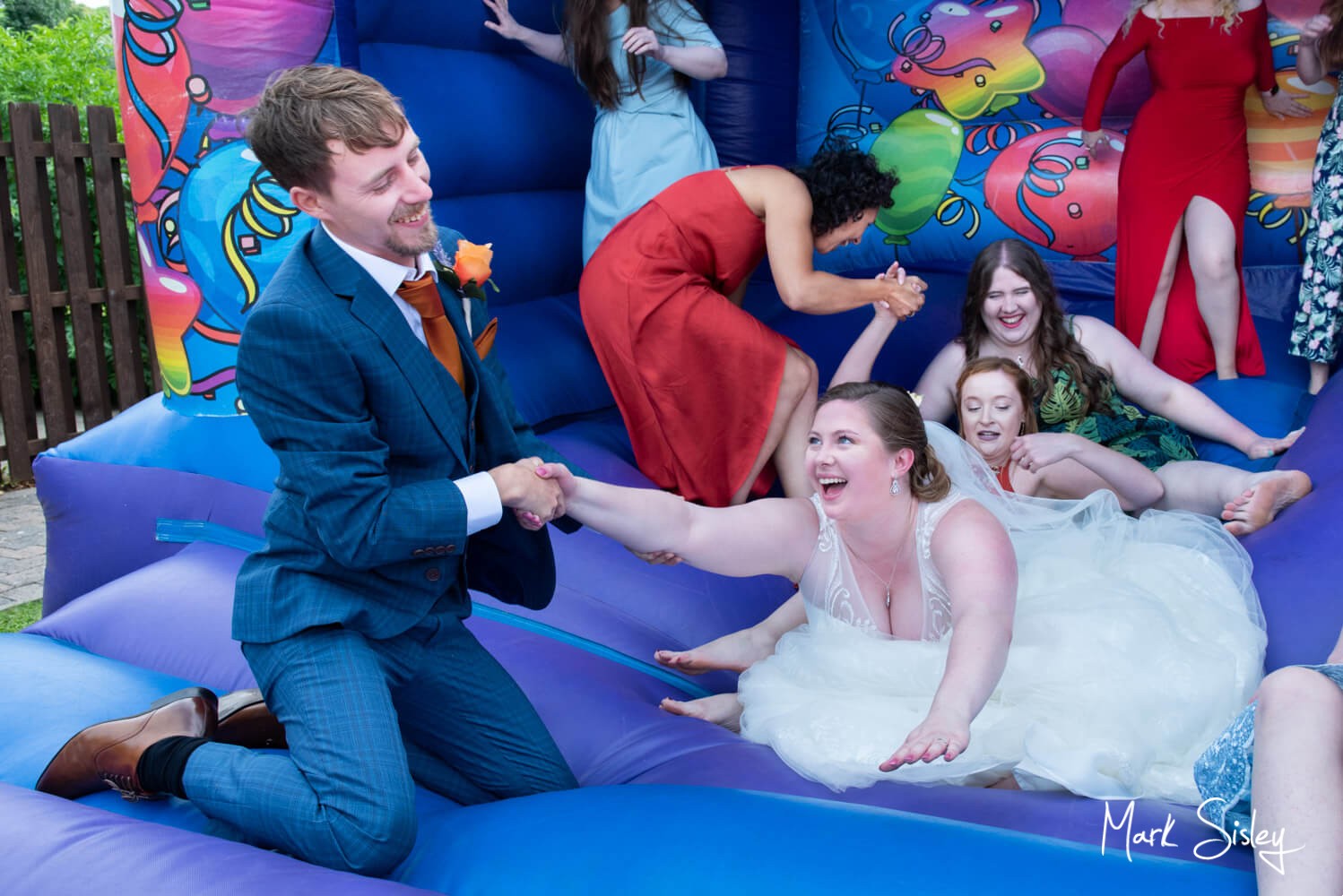 Fun photography of the groom as he rescues his bride from the bouncy castle - Lambert Hotel wedding near Thame 