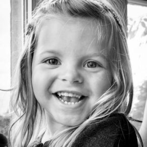 Black and white wedding photography in Buckinghamshire - young girl laughing at Eynsham Hall