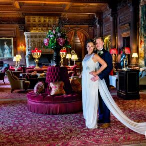 Bride and groom in the Great Hall at Cliveden House, with rich red and gold furnishings, by Mark Sisley Photography
