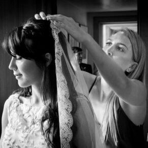Classic wedding photography Buckinghamshire of the bride having her veil adjusted at The Dairy, Waddesdon
