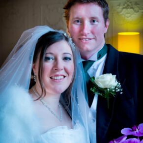Window-lit image of bride and groom at Stoke Place wedding