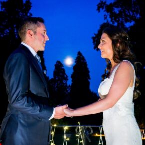 Bride and groom at dusk at Taplow House Hotel with moon rising and fairy lights on railing