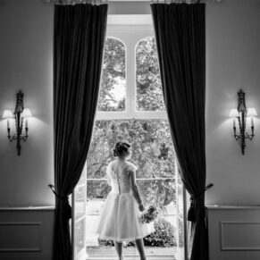 Black and white dramatic window-lit image of bride at Taplow House Hotel wedding