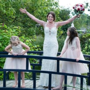 Photography of the happy bride messing about on the bridge at Sopwell House with her two gorgeous wedding flower girls 