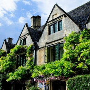 The Bay Tree Hotel's honey coloured historic Cotswold stone exterior is adorned with a climbing wisteria plant for this wedding photography shot