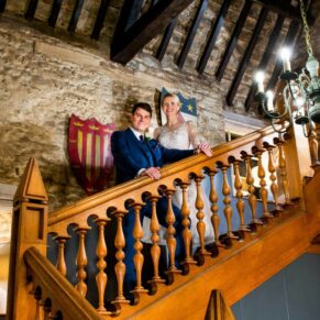 Photography of the bride & groom as they strike a pose on the grand old staircase at their Bay Tree Hotel wedding in Burford