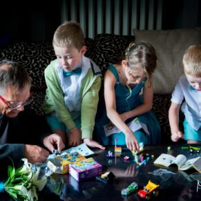 Photography of the children playing a board game and lit with atmospheric window lighting during the drinks reception at this Beaumont Estate wedding 