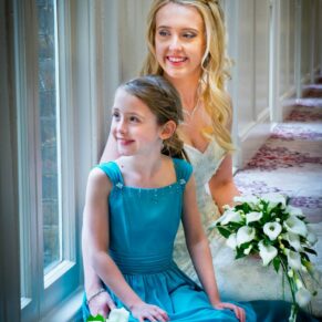 Photography of the bride with her bridesmaid sat on the ground inside the Beaumont Estate's historic passageway on her wedding day