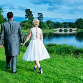 The smiling newlyweds stroll hand in hand away from the camera on this glorious sunny day