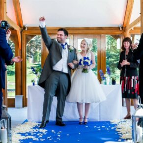 The groom thumping the air after the ceremony in celebration whilst holding his bride's hand
