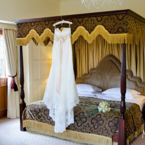The bride's gown hung up on the four poster bed in the stunning bridal suite 