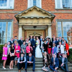 A large formal family group wedding pose on the front steps of Dorton House in Buckinghamshire