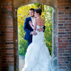 The newlyweds captured full length through an archway during golden hour at their Dorton House wedding reception