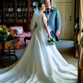 The newlyweds look out of the window surrounded by the grand interiors of the main building at Hartwell House 