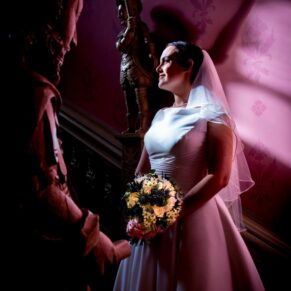 The bride illuminated with very dramatic high contrast lighting on the staircase at Hartwell House