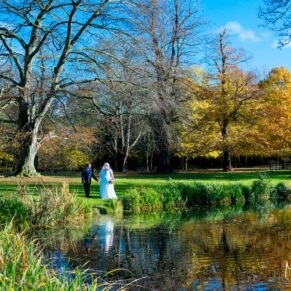 Autumn colours for the newlyweds as they take a stroll by the lake in the gardens of Hartwell House 
