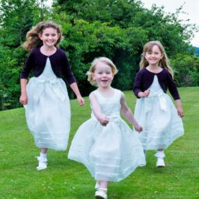 The giggling flower girls running through the gardens towards the camera 