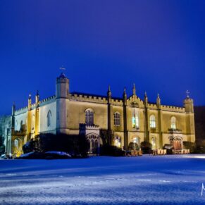 The historic exterior captured at dusk with floodlighting and shrouded under a blanket of gorgeous white snow