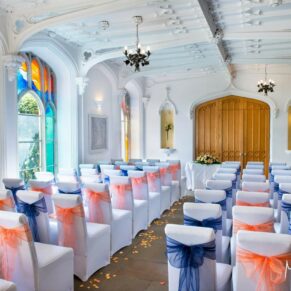 Striking Garden Room interior with a blue and orange themed chair covers at this marriage ceremony