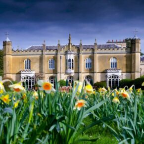 The Grade I listed property under a stormy grey sky with spring daffodils filling the foreground at this spring marriage 