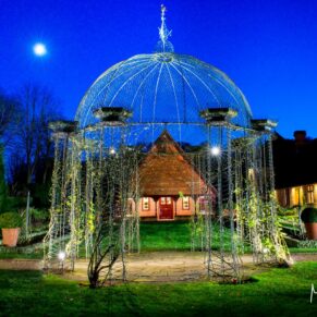 The Dairy's rose arbour beautifully floodlit at dusk with the moon glowing brightly in the deep blue sky