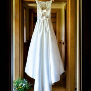 The bride's gorgeously detailed gown hanging up in a doorway at The Dairy