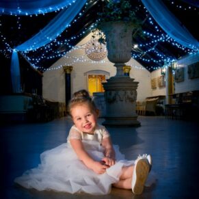 Adorable flower girl sat on the dancefloor and lit with dramatic lighting during this wedding reception at The Dairy 