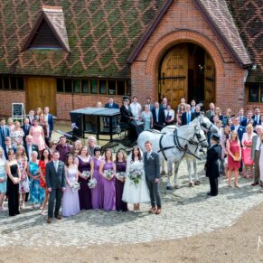 Everyone in the entrance courtyard being photographed with the horses and carriage on this wedding at The Dairy