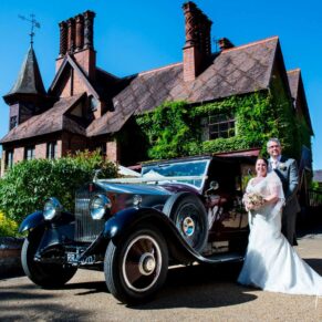 The newlyweds with their car at the back of the hotel