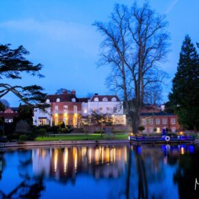 A romantic night shot of Saint Michael's Manor across the water under dusky blue skies 