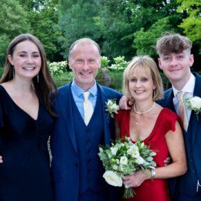 The bride and groom pose for a picture with their children in the colourful gardens of Saint Michael's Manor