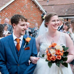 Reportage photography of the newlweds exiting the ceremony at their Mercure Lambert Hotel wedding, Thame