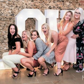 The bride's girlfriends enjoying the party atmosphere during the evening reception as they lark around by the giant LOVE letters  