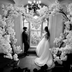 The newlyweds captured in one of the many gorgeous stained glass windows with a giant flower arch on their special day 