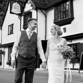 The bride and groom take a relaxed stroll outside the front of The Olde Bell in Hurley on their wedding day