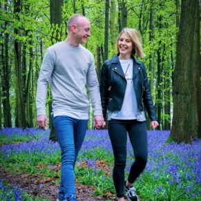 A couple walk through the bluebells in a Buckinghamshire woodland scene for their relaxed engagement portraits photography sessiony 