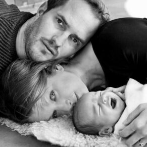 Parents and their baby laying on the ground for a dramatic black and white photography pose for their Buckinghamshire family portraits photo-shoot