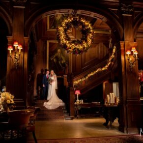 Cliveden House interior of the Great Hall at Christmas with the newlyweds positioned on the staircase during their wedding reception 