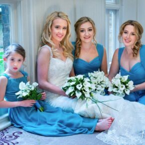 The bride and bridesmaids take a seat on the ground for a casual photography pose indoors at this lovely relaxed Beaumont Estate wedding 