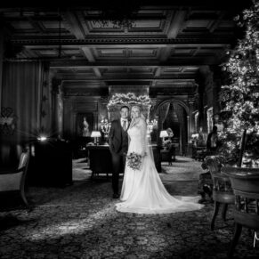 Low light black and white wedding photography of the newlyweds in the Great Hall at Cliveden House in Buckinghamshire