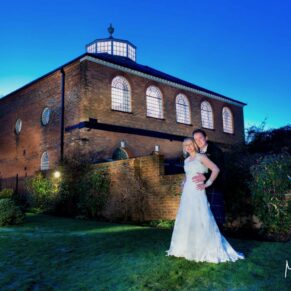 Night shot of the bride and groom under dusky blue skies outside the Kings Chapel in Old Amersham 
