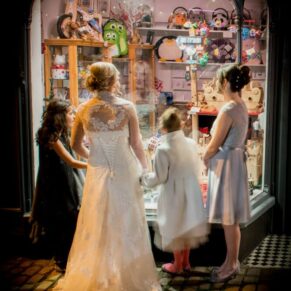 The ladies glance into a window after stepping into the high street for some photo opportunities during this Kings Chapel wedding in Old Amersham 