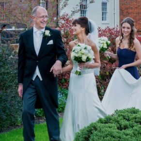 The newlyweds walking through the grounds with their bridesmaids at their Kings Chapel wedding in Old Amersham 