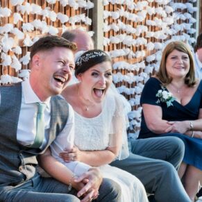 Buckinghamshire Marquee Wedding Photography - the newlyweds loving the speeches judging by their smiles