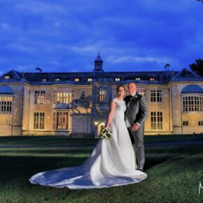 Buckinghamshire Winter Wedding Photography - the newlyweds pose in front of floodlit Hartwell House