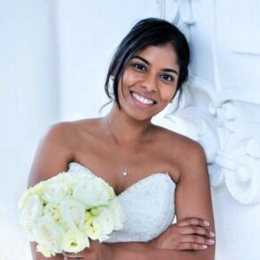 The bride strikes a smiley pose beside Danesfield House's stone emblem under the main entrance arch on her wedding daye Danesfield House's stone emblem under the main entrance arch