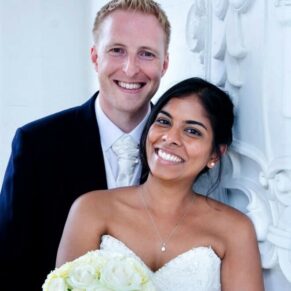 The newlyweds pose for a close-up portrait beside Danesfield House Hotel's stone emblem in the entrance arch on wedding day    